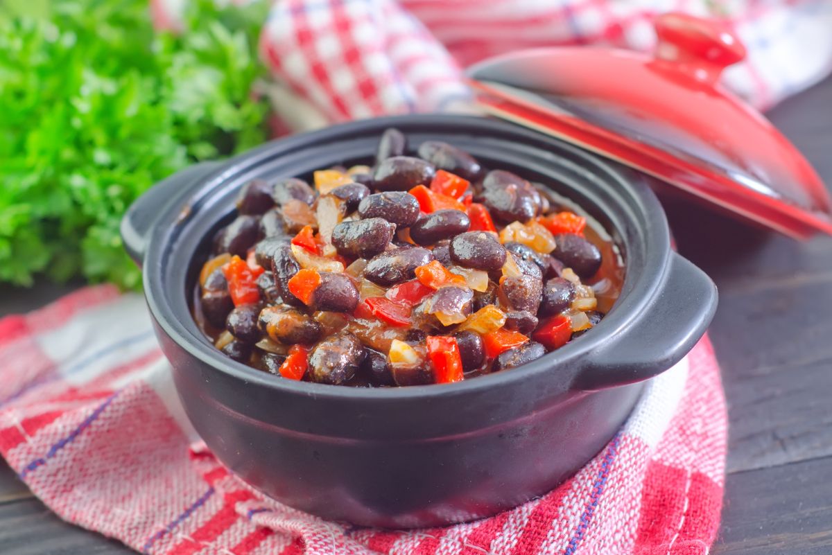 Weight Watchers Black Bean and Lentil Chili in a black pot sitting on a red and white tablecloth.