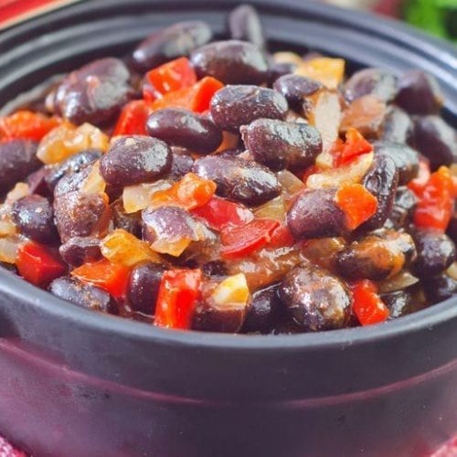 Black Bean and Lentil Chili in a black bowl sitting on a red and white checked tablecloth.