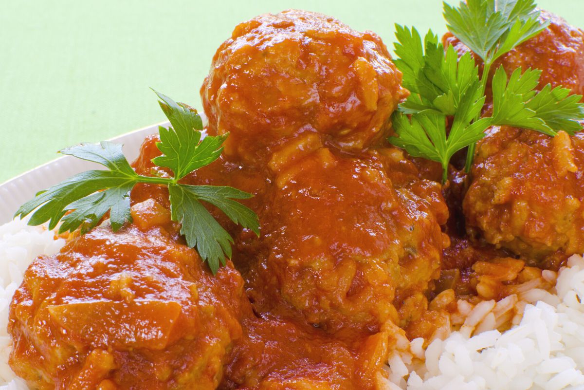 Weight Watchers Sweet and Sour Turkey Meatballs on a bed of rice. A light green background.