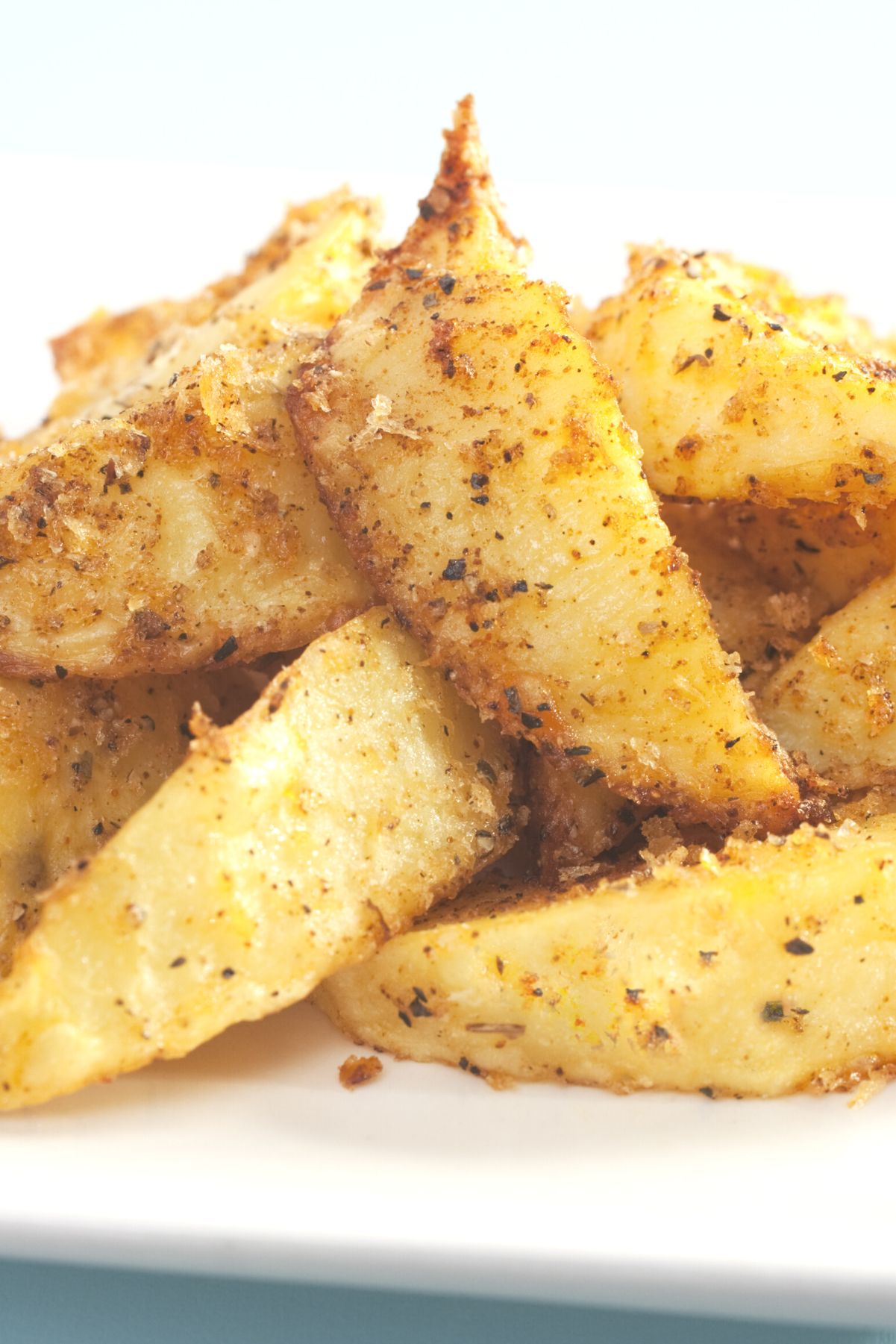 Closeup of a pile of Baked Cumin Fries on a white plate.