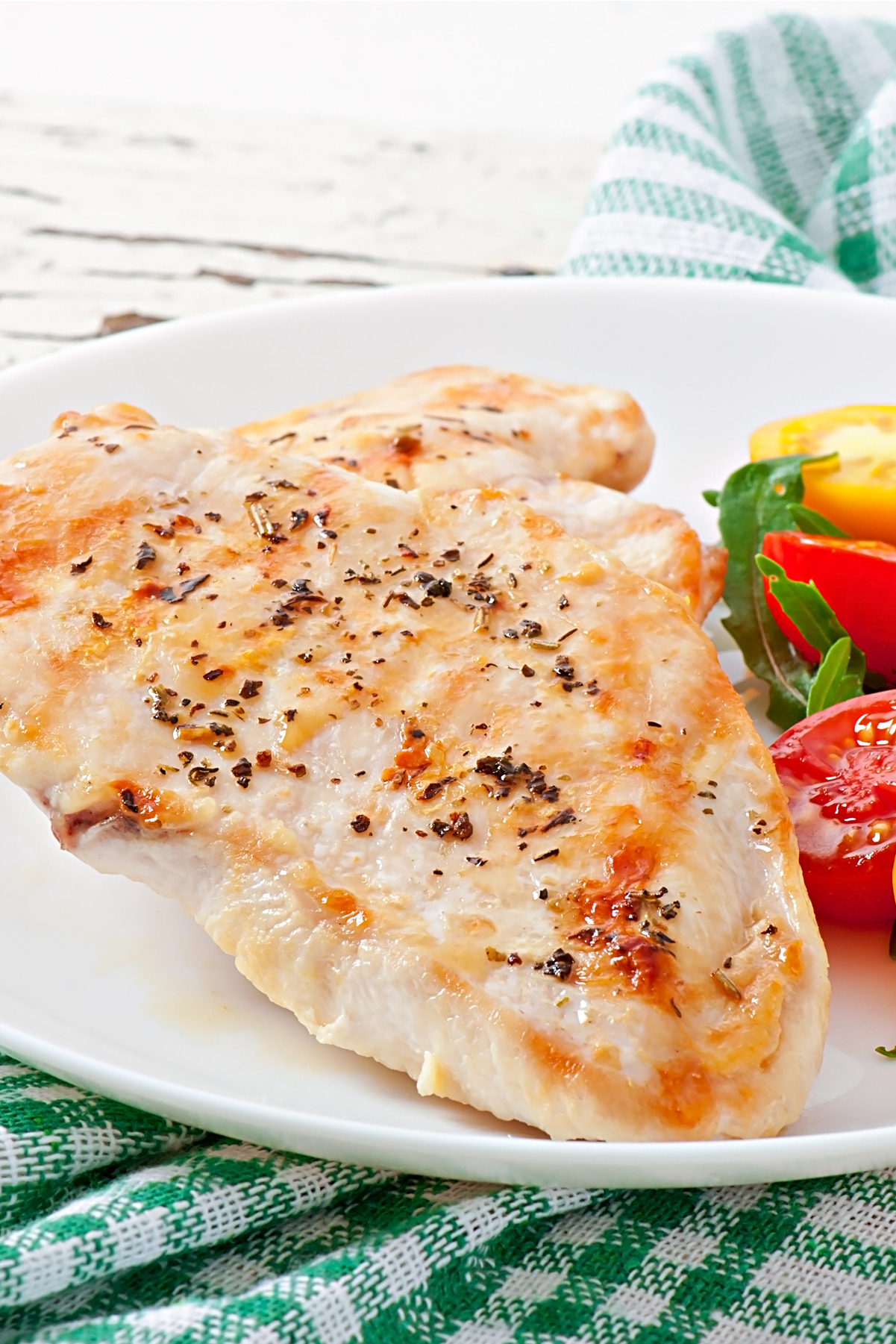 Weight Watchers Lemon and Herb Chicken on a white plate with red and yellow cherry tomatoes