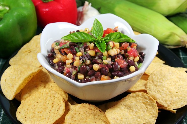 Weight Watchers Vegan Salsa Dip in a white bowl surrounded by tortilla chips with bell peppers in the background.