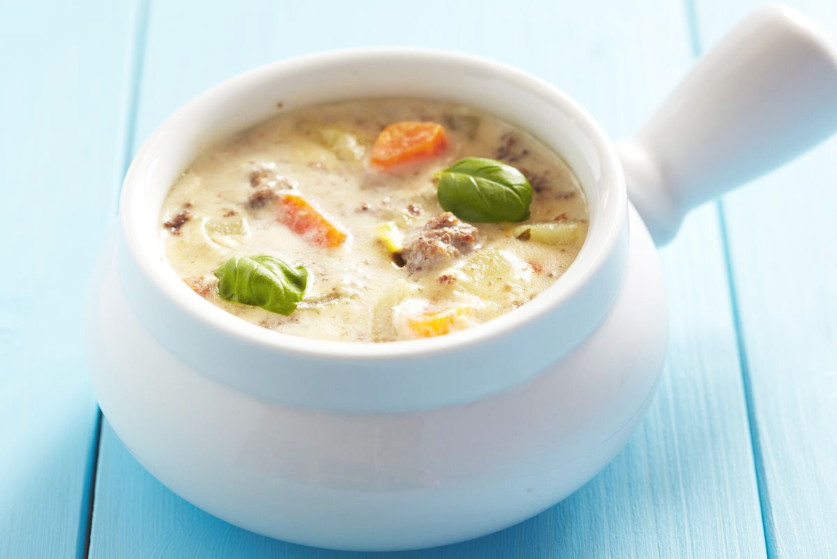 Weight Watchers Cheeseburger Soup in a white crock on a blue background.