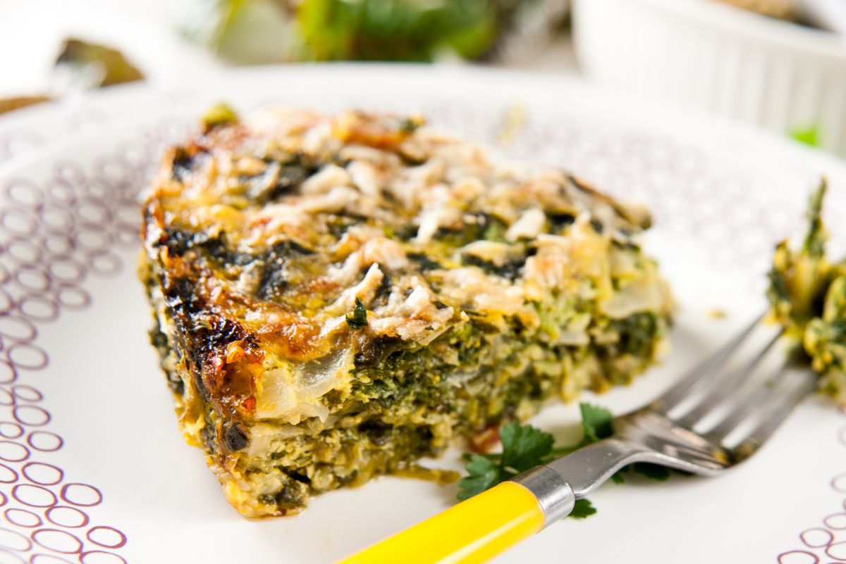 Weight Watchers Spinach Souffle on a white plate with a fork with a yellow handle.