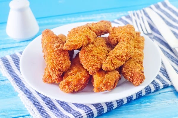 Weight Watchers Easy Buffalo Chicken Tenders on a white plate sitting on a blue and white striped towel.