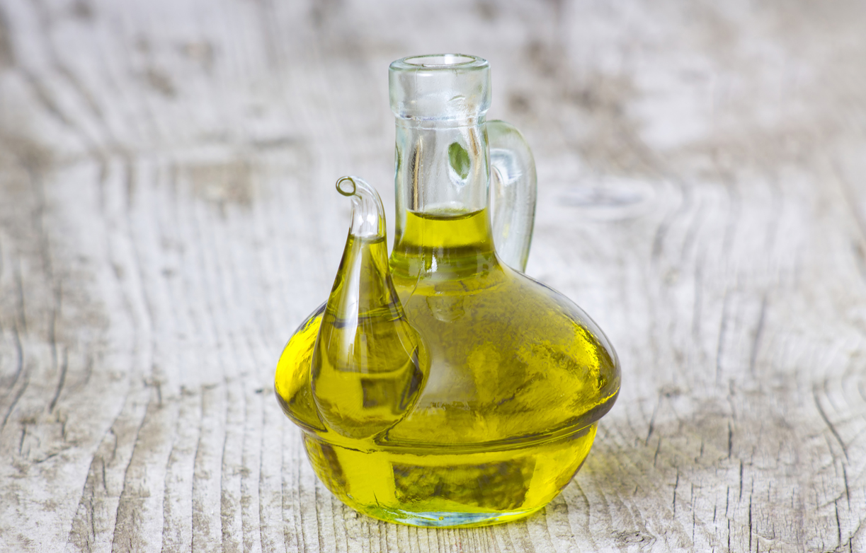 Olive oil in a bottle on wooden background.