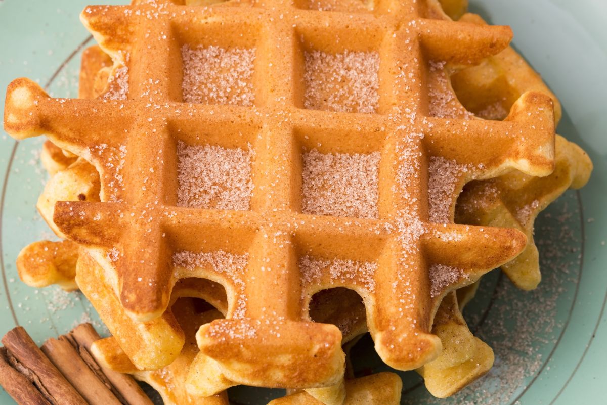 Closeup of Weight Watchers Pumpkin Waffles on a light green plate with cinnamon sticks.