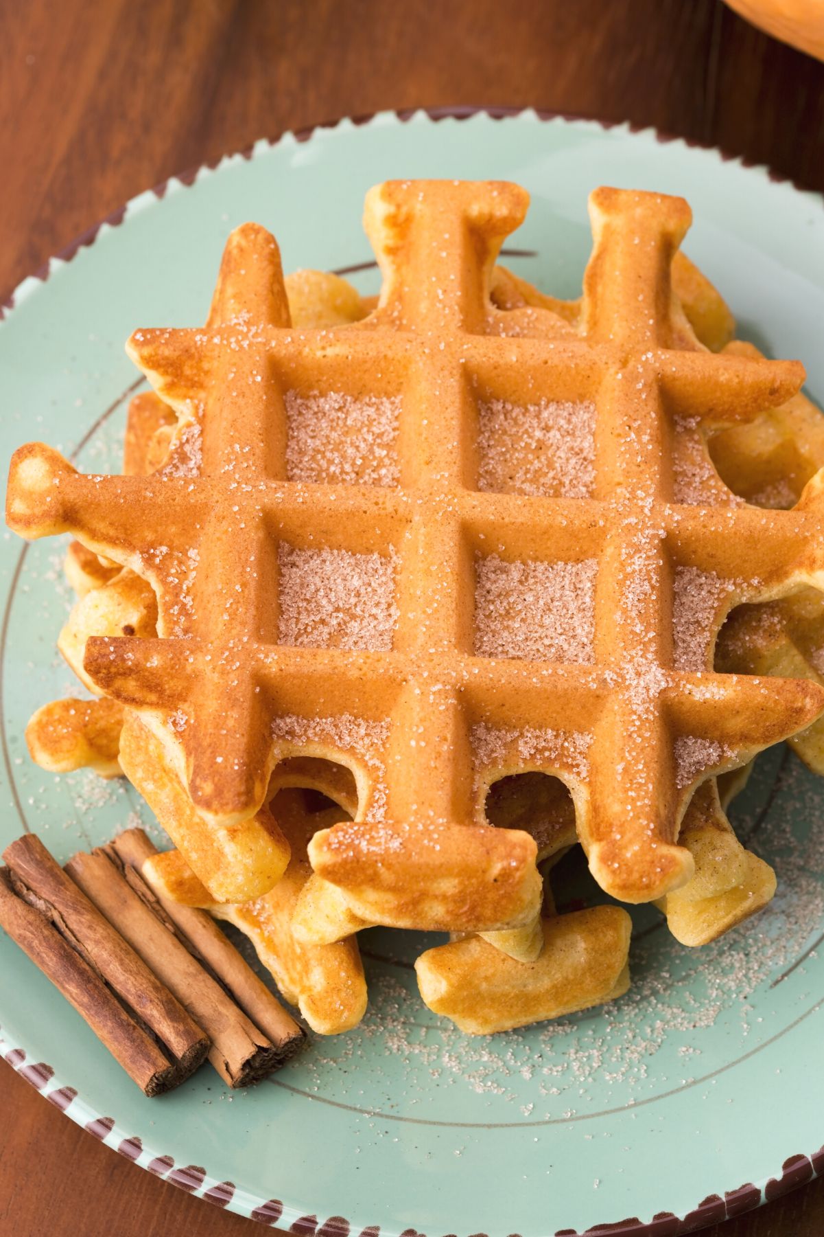 2 Weight Watchers Pumpkin Waffles stacked on a light green plate with cinnamon sticks.