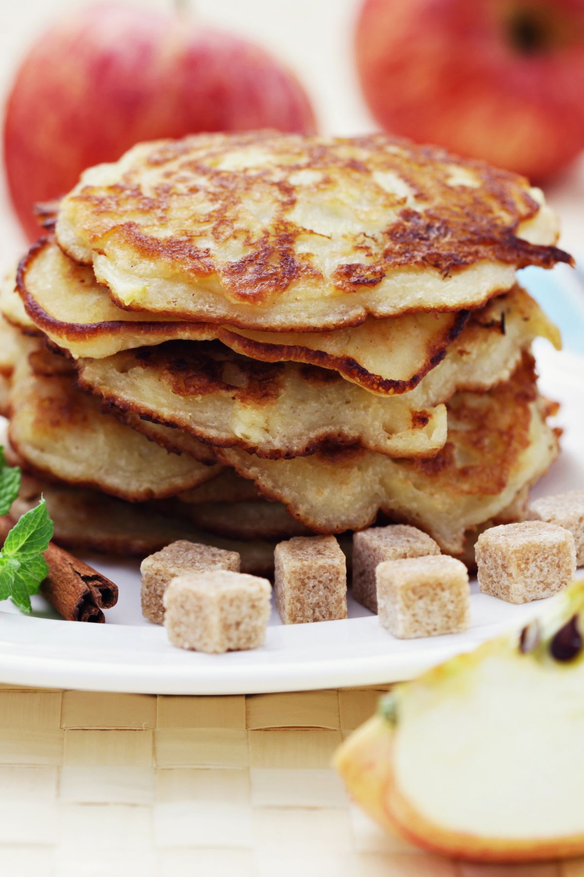 A stack of Fall Favorite Cinnamon Apple Pancakes on a white plate with cinnamon.