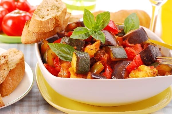 Ratatouille in a white bowl sitting on a yellow plate.