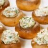 Artichoke stuffed mushrooms baked until golden brown, filled with a creamy artichoke and herb mixture. Mushrooms are arranged on a white plate with visible flecks of fresh dill, showing a smooth, cheesy filling and tender mushroom caps in close-up food photography.