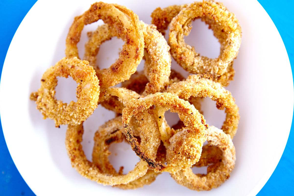 Overhead view of Weight Watchers Crispy Onion Rings Recipe on a white plate on a bright blue background.