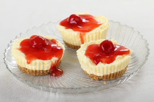 Weight Watchers Mini Cheesecakes with cherry pie filling on top on a clear glass plate.