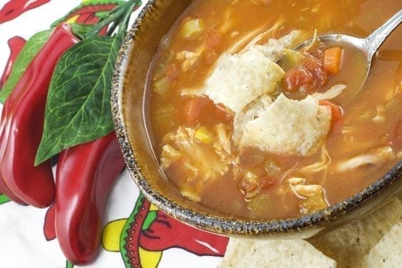 Weight Watchers Tortilla soup in a dark bowl with peppers next to it.