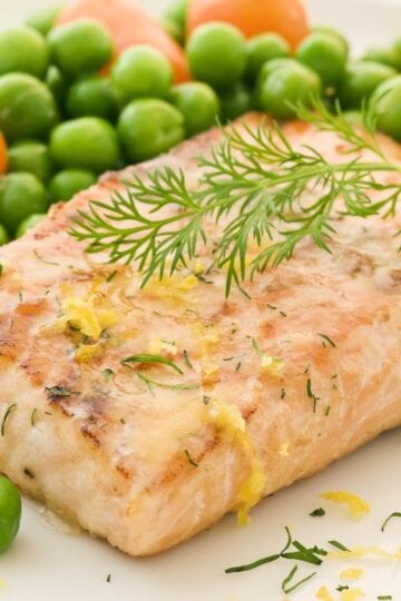 Closeup of Weight Watchers Healthy Parchment Salmon on a white plate with peas.