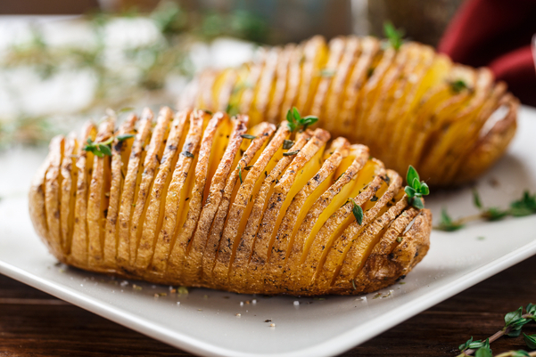 2 WW Air Fryer Hasselback Potatoes  on a white plate, with an out of focus background.