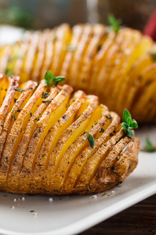 Closeup of 2 WW Air Fryer Hasselback Potatoes on a white plate.