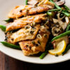 Weight Watchers Italian Chicken Piccata on a white plate with green beans and a lemon slice.