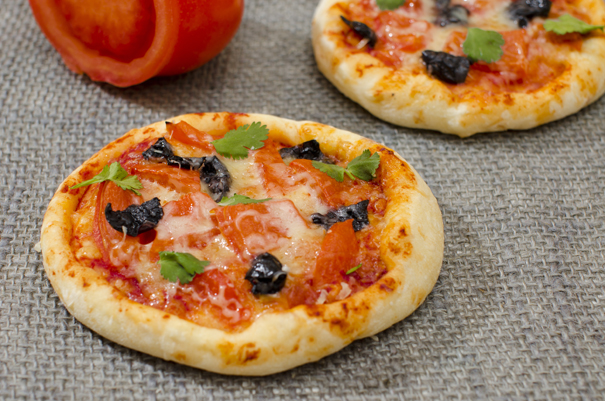 Two Weight Watchers Pita Pizzas with a tomato in the background.