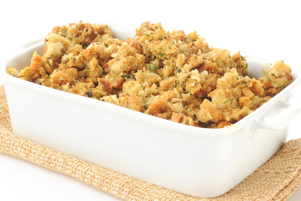 Weight Watchers Homemade Stuffing in a rectangular, white casserole dish, sitting on a tan napkin. White background.