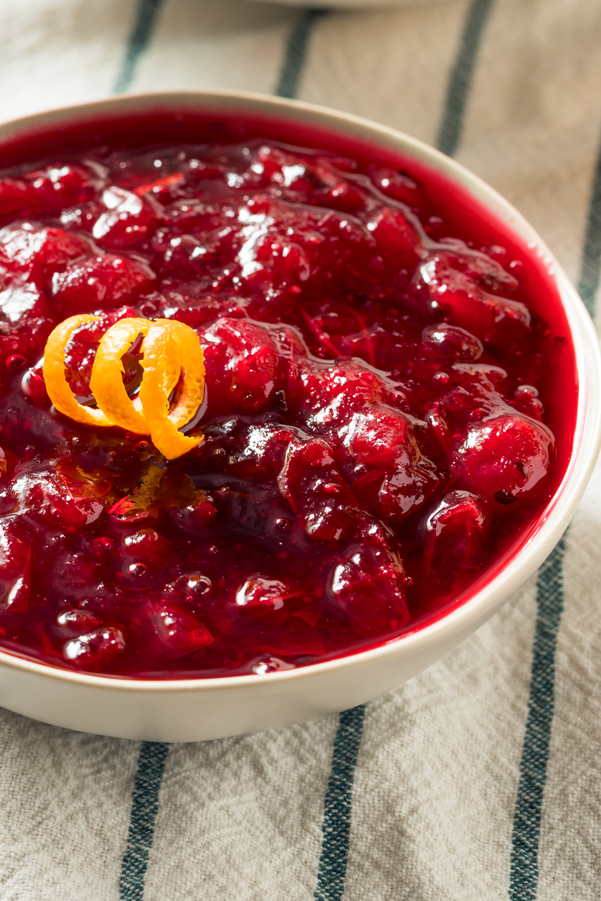 Closeup of Weight Watchers Cinnamon Apple Cranberry Sauce in a white bowl sitting on a white with blue stripes cloth.
