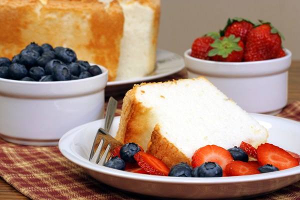 A slice of Weight Watchers Angel Food Cake on a white plate with fruit.
