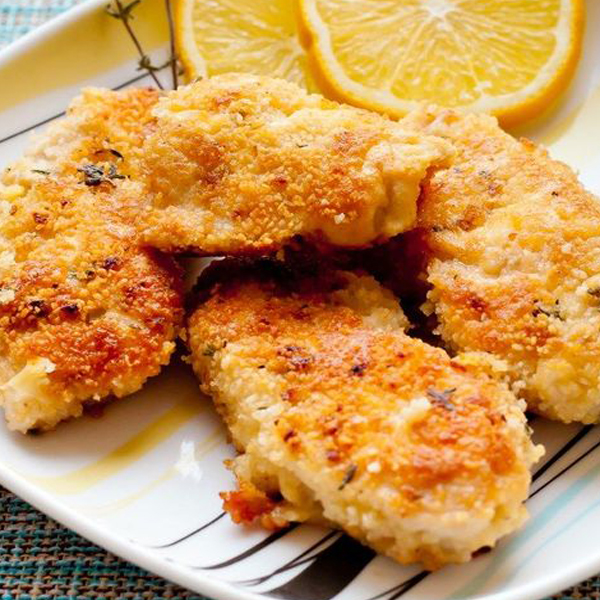 Parmesan Chicken on a white plate with orange slices.