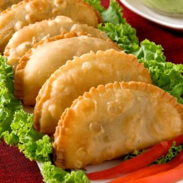 Weight Watchers Vegetarian Indian Samosa lined up on a lettuce lined, rectangular plate.