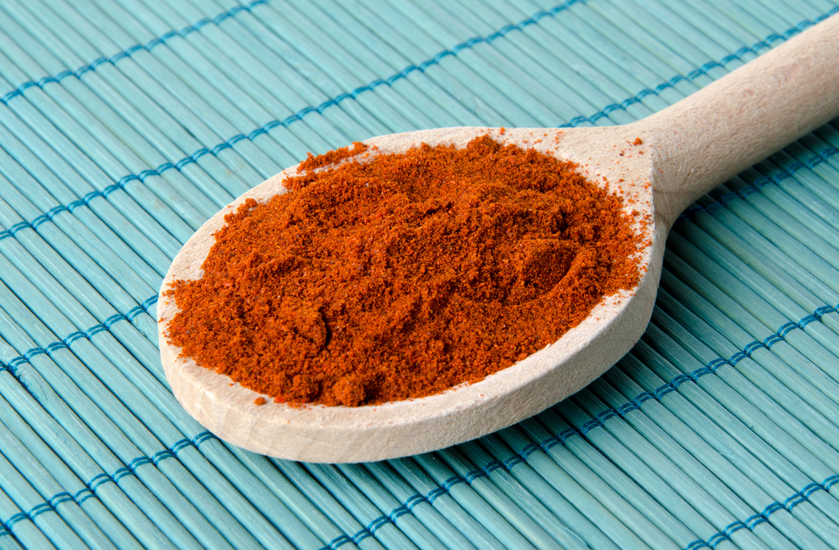 Paprika on a wooden spoon on top of a blue mat.