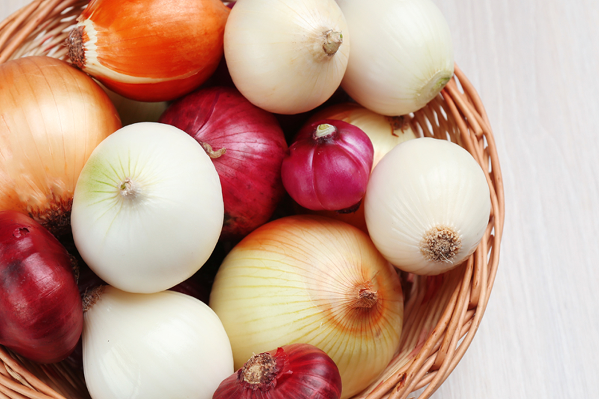 A variety of onion types in a basket.