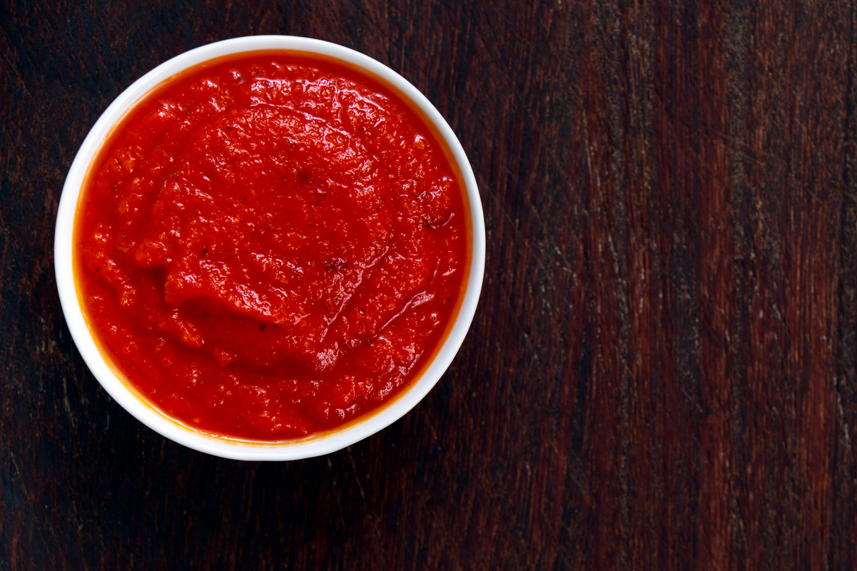 Marinara sauce in a white dish on a dark background.