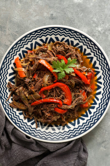 Weight Watchers Slow cooker Ropa Vieja in a blue and white bowl on a gray table.