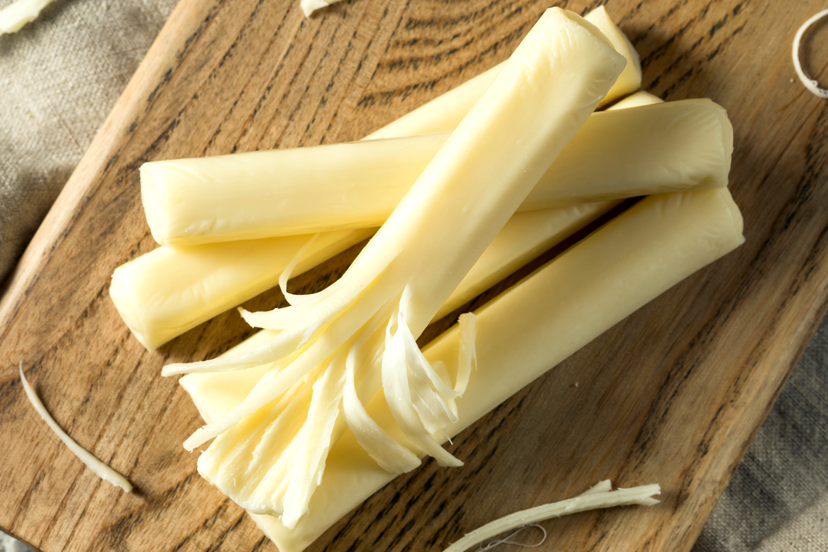 A pile of string cheese on a cutting board.