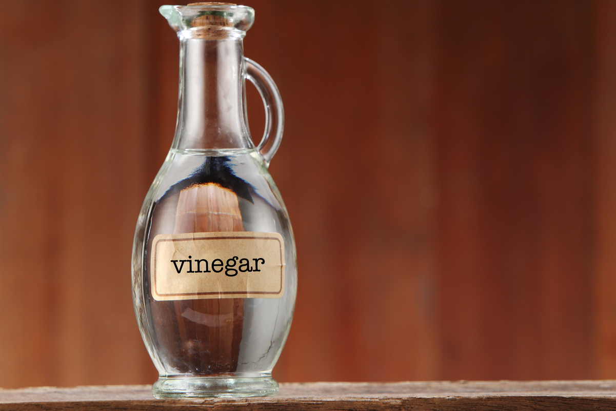 A bottle of white vinegar with a brown background.