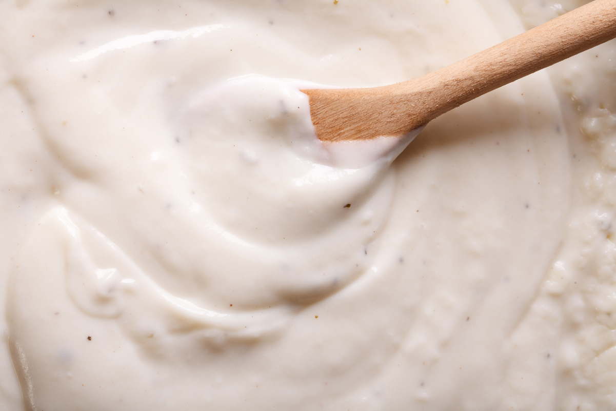 Closeup of Weight Watchers Bechamel Sauce with a wooden spoon in it.