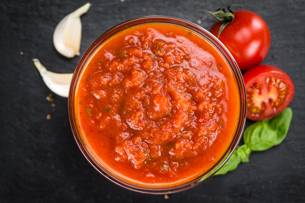 Easy Homemade Weight Watchers Tomato Sauce in a glass bowl with fresh garlic and tomatoes around it.