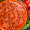 Closeup of Easy Homemade Weight Watchers Tomato Sauce in a glass bowl with tomatoes next to it.