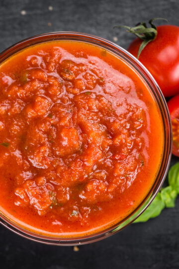 Closeup of Easy Homemade Weight Watchers Tomato Sauce in a glass bowl with tomatoes next to it.