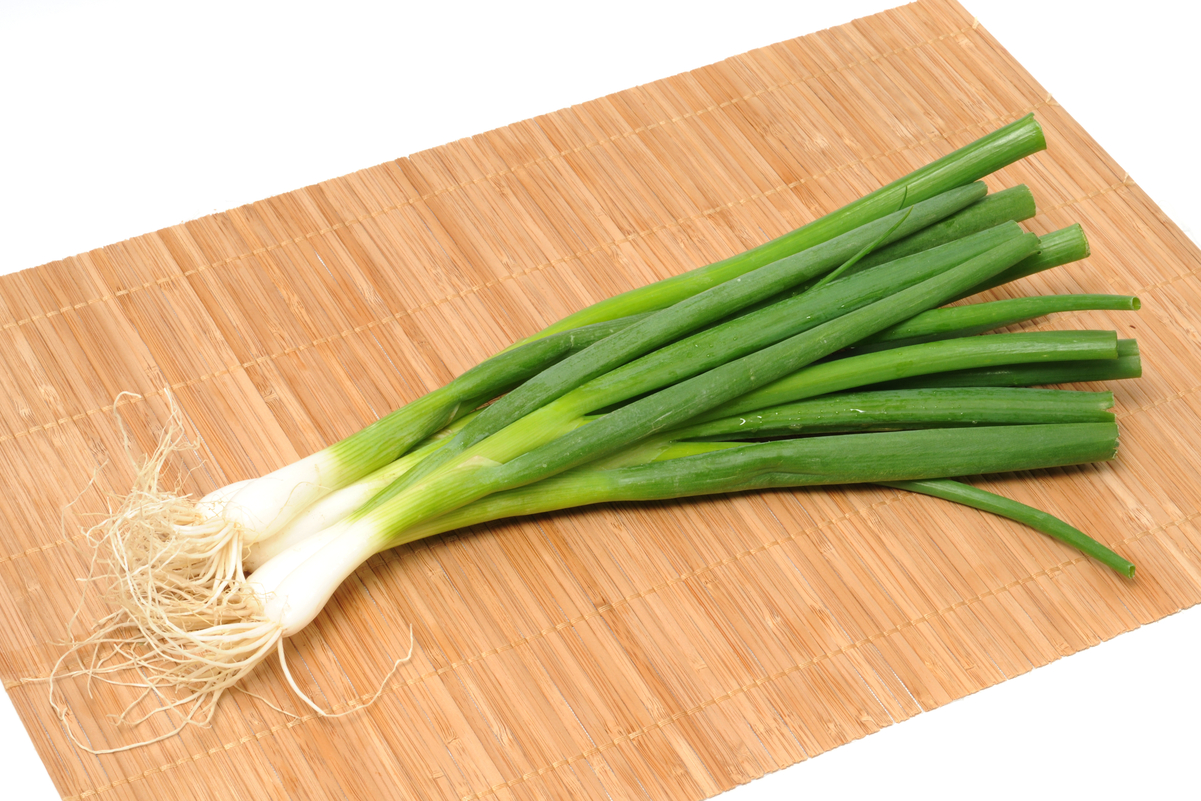 Green onions on a tan place mat.