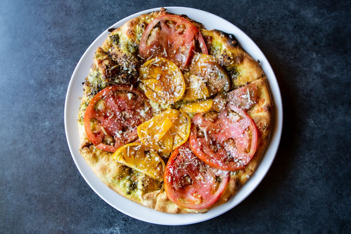 Overhead view of Weight Watchers Tomato Basil Pizza on a white plate, on a dark blue surface.