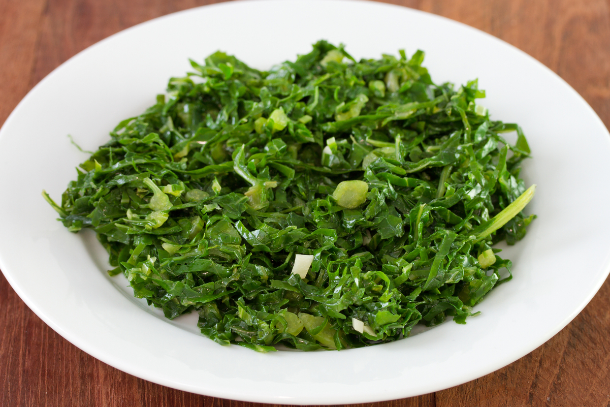 Weight Watchers Lemon Garlic Kale in a shallow white bowl on a wooden surface.