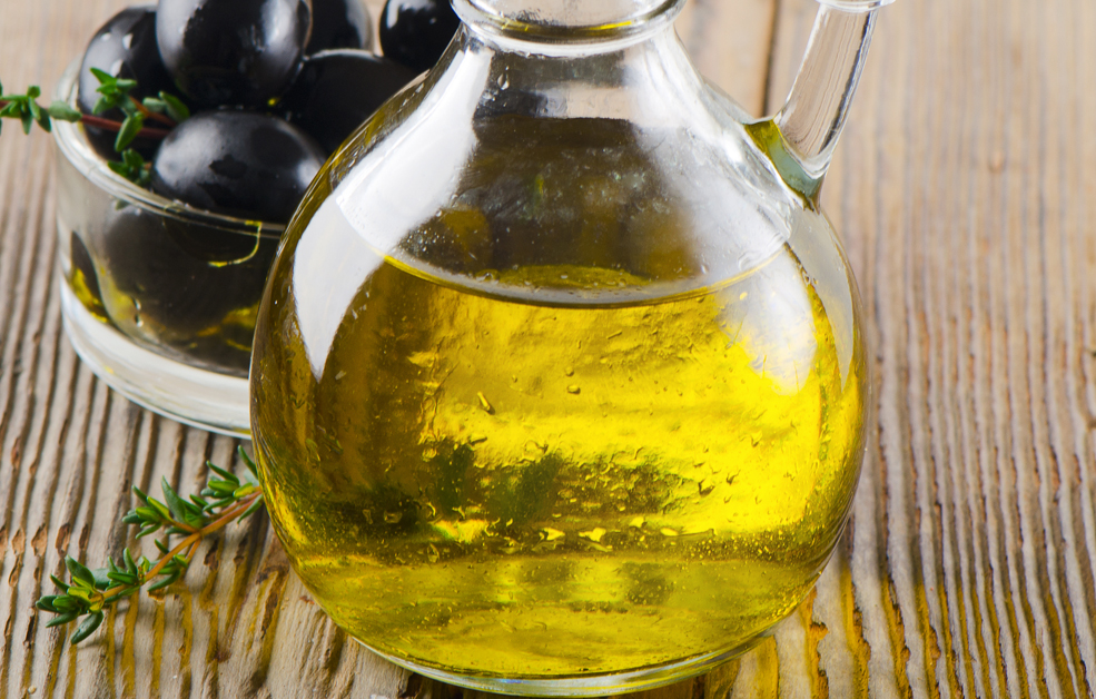 Olive oil and black olives on a wooden table.