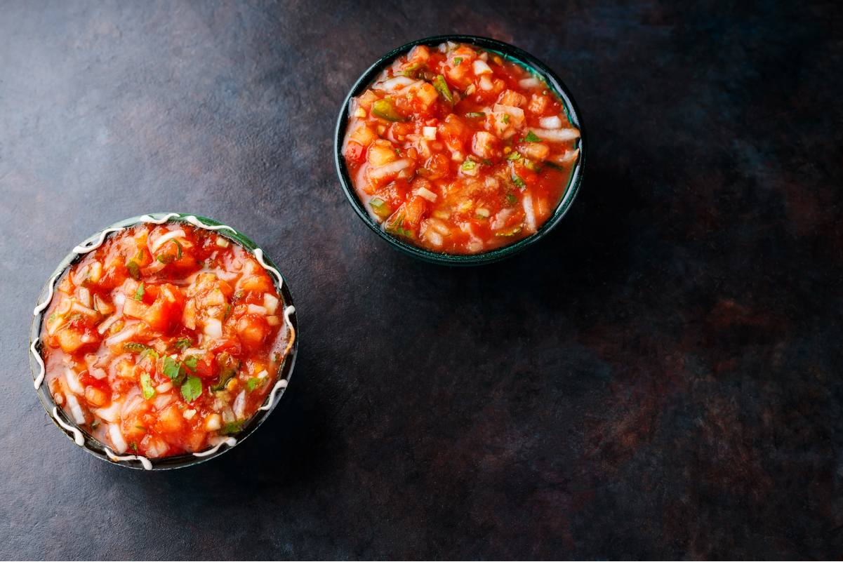 2 small bowls of salsa on a black, slate background.