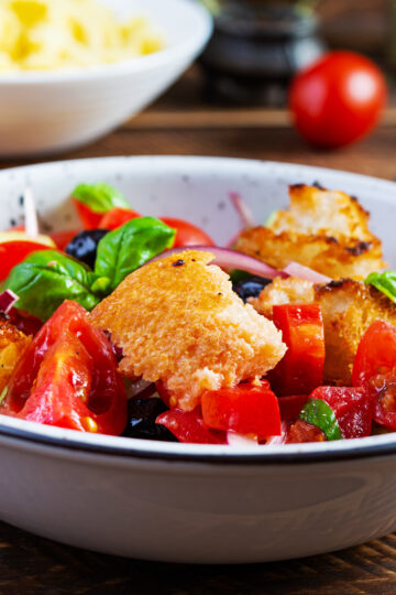 Weight Watchers Tomato Salad with Grilled Italian Bread in a white bowl with ingredients behind it.