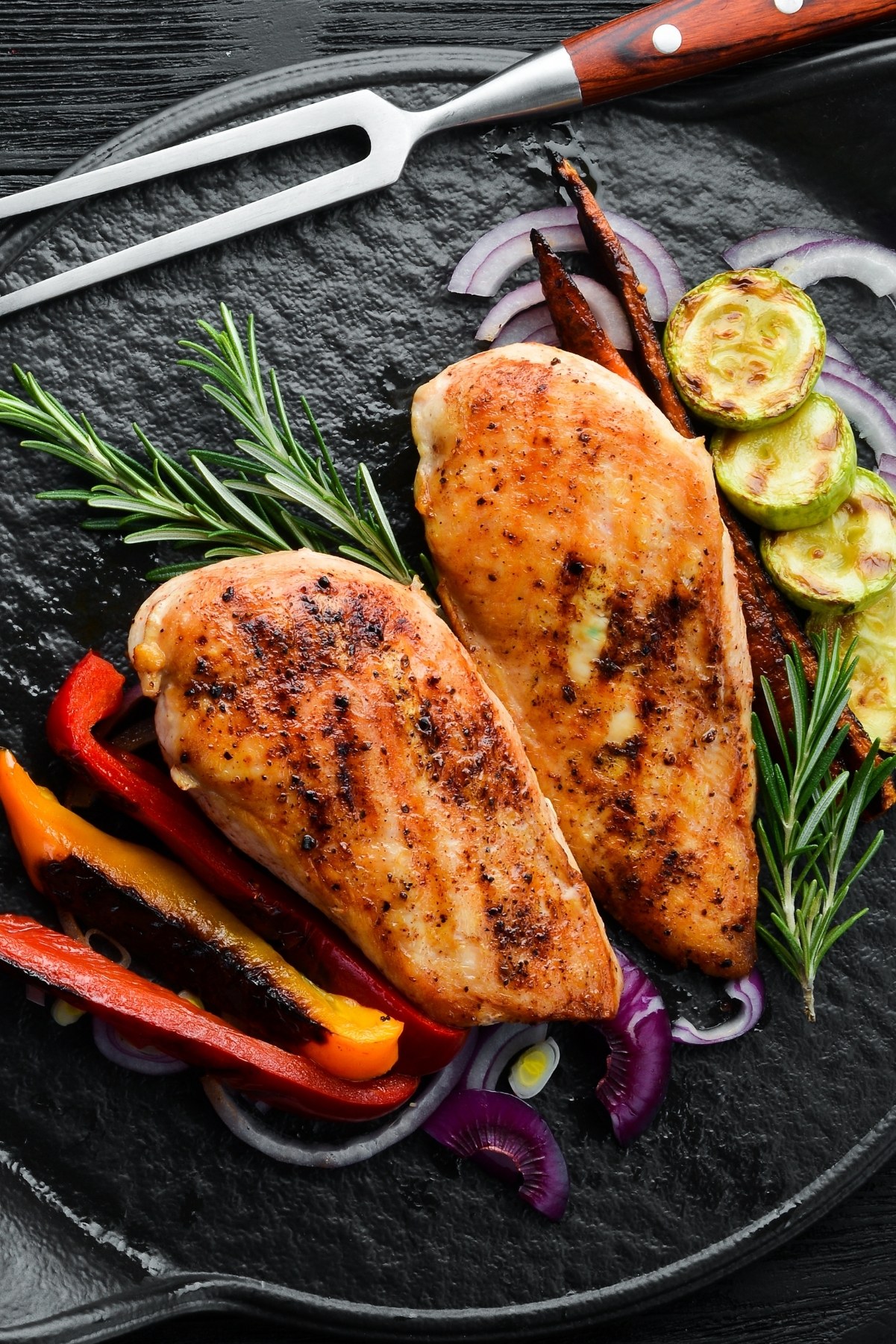 Weight Watchers Grilled Lemon and Herb Chicken Breast on a black surface with grilled vegetables.