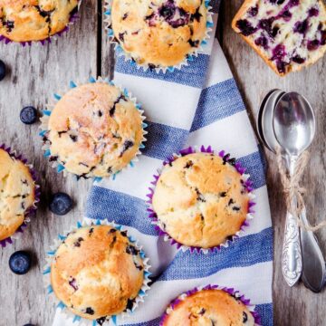 Weight Watchers Best Blueberry Muffins on a white and blue cloth sitting on a rustic wood surface.