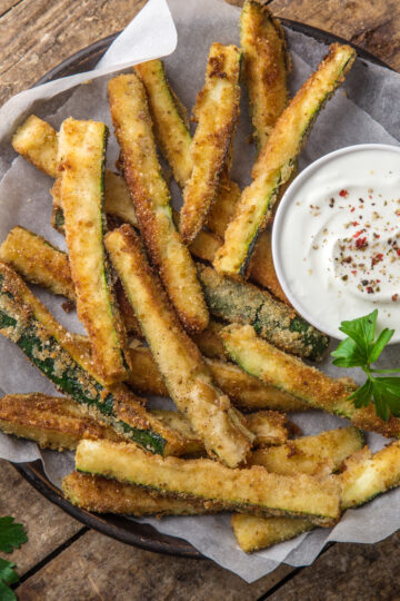 Closeup of Weight Watchers Dill and Lemon Zucchini Fries on a white paper surface.