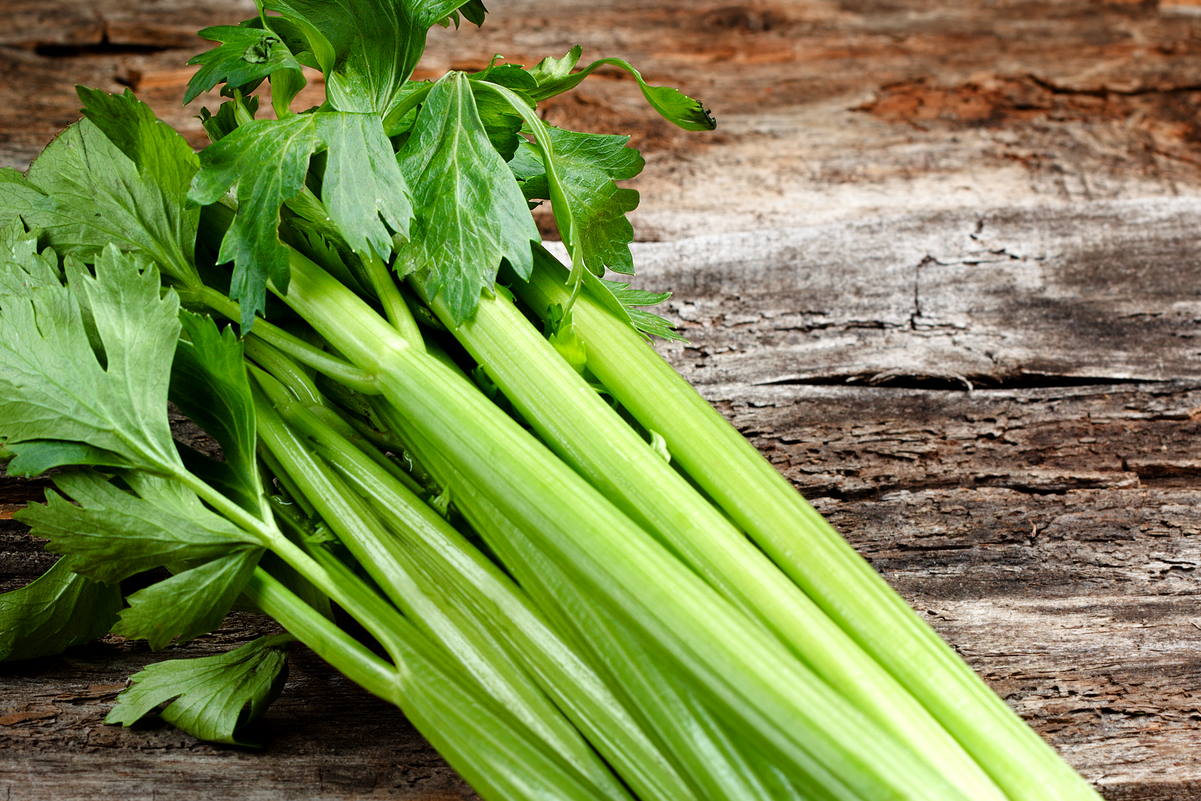 Celery stalks on a rustic wooden surface.