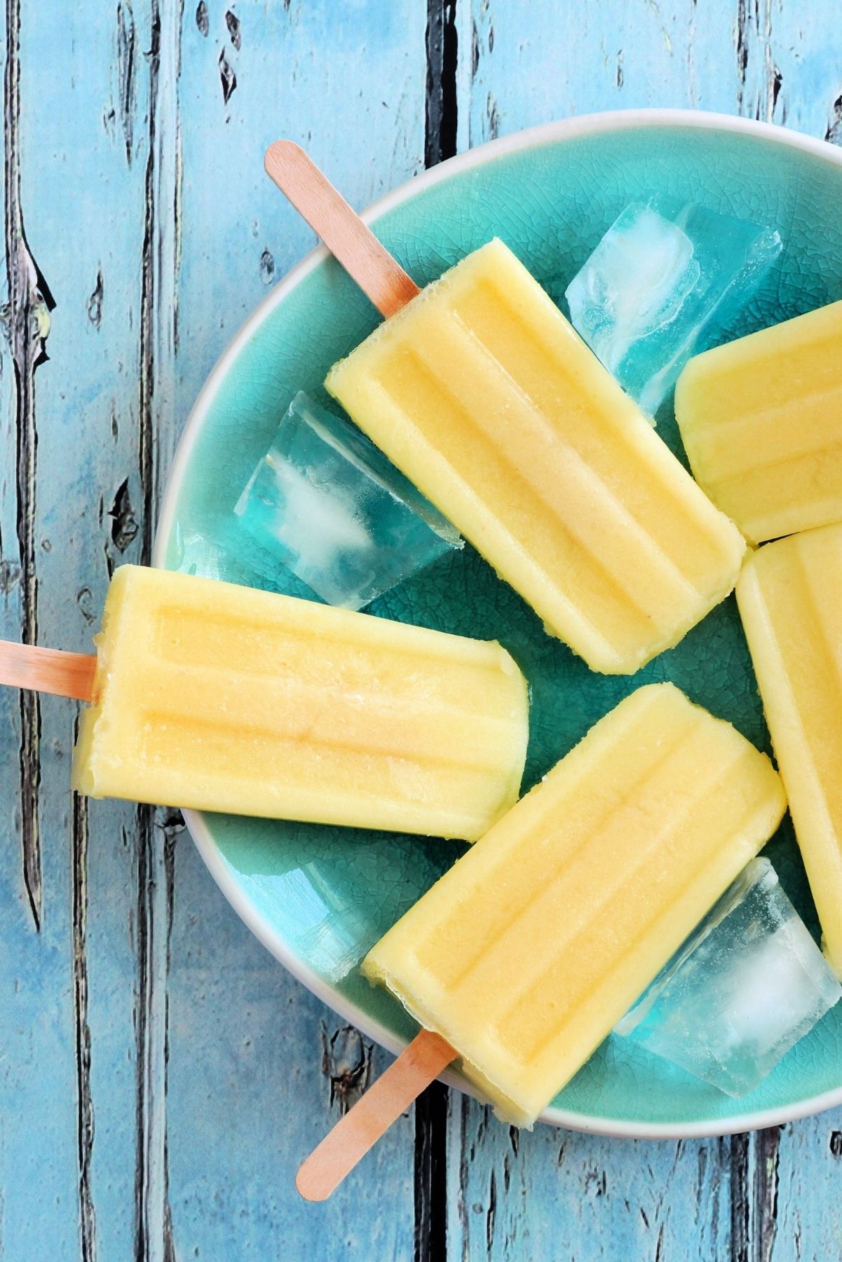 Closeup of Weight Watchers Chipotle Pineapple Popsicles on a blue plate sitting on a rustic blue surface.