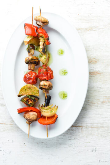 2 Easy Grilled Weight Watchers Vegetable Kabobs on a white plate sitting on a light rustic surface.